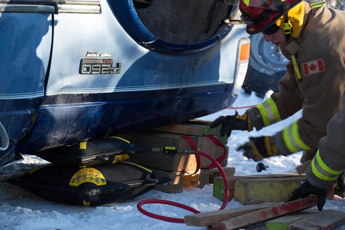 A member positioning a lifting air bag under a pickup truck during training